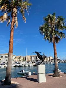 eine Pelikan-Statue in einem Jachthafen mit Palmen in der Unterkunft Chez virginie : Appartement lumineux au calme. in Fréjus