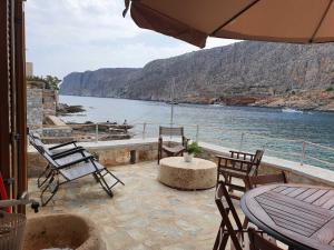 een patio met een tafel en stoelen en uitzicht op het water bij MiloPetra in Yerolimin