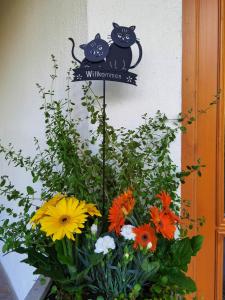 a sign with two cats on it next to flowers at Hotel Landhaus Zell am See in Zell am See