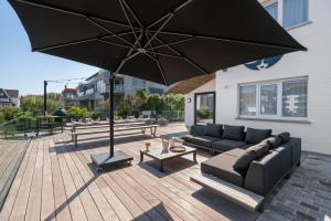 patio z kanapą i dużym parasolem w obiekcie Villa Paradis - De ultieme kustvilla met zwembad ! w mieście Koksijde