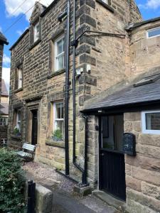 an old brick building with a black door and a bench at Dene Cottage in Stanton in Peak