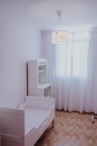 a white bed in a room with a window at Casa Familiar Tarragona playa in Tarragona