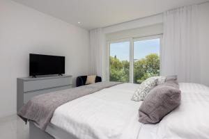 um quarto branco com uma cama grande e uma janela em Amarie 2 em Dramalj