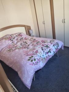 a bed with a pink bedspread with flowers on it at Skipsea sands holidays in Ulrome