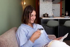 una mujer sentada en un sofá sosteniendo una taza de café en Aparthotel Timmerfabriek Apartments I Kloeg Collection, en Vlissingen