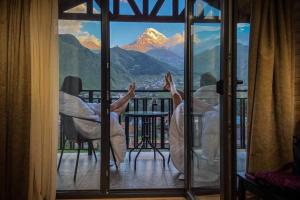 two people sitting on a balcony looking out of a window at Aronia Kazbegi in Stepantsminda