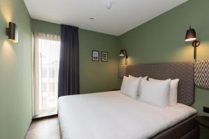 a bedroom with a bed with white pillows and a window at Aparthotel Timmerfabriek Apartments I Kloeg Collection in Vlissingen