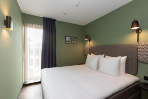 ein Schlafzimmer mit einem Bett mit weißen Kissen und einem Fenster in der Unterkunft Aparthotel Timmerfabriek Apartments I Kloeg Collection in Vlissingen