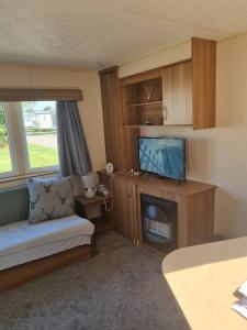 a small living room with a couch and a television at Skipsea sands holidays in Ulrome