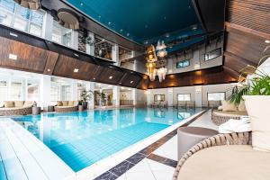 a swimming pool in a hotel with chairs and tables at IMLAUER Hotel Schloss Pichlarn in Aigen im Ennstal