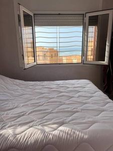 un letto bianco in una camera da letto con due finestre di Sunset Villa by the Ocean a Ibekhchach