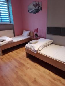 two beds in a room with pink walls and wooden floors at Dom Brama Mazur in Ostróda