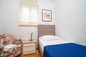 a small bedroom with a bed and a chair at Apartments Villa Ivka in Dubrovnik