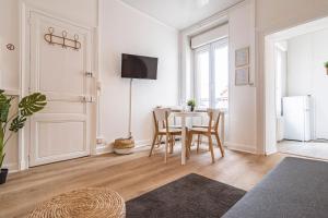 ein weißes Wohnzimmer mit Tisch und Stühlen in der Unterkunft Le Zola - charmant 2 chambres - centre gare in Reims