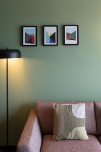 ein Sofa mit Kissen und drei Bilder an der Wand in der Unterkunft Aparthotel Timmerfabriek Apartments I Kloeg Collection in Vlissingen
