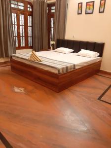 Cama grande en habitación con suelo de madera en PAARIJAAT Homestay & Guesthouse en Ayodhya