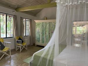 a bedroom with a bed with a canopy and windows at Diklande Estate Bungalow in Negombo