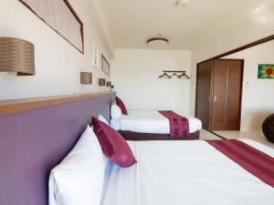 2 Betten in einem Hotelzimmer mit Lila und Weiß in der Unterkunft Cozy Stay In Itoman in Itoman