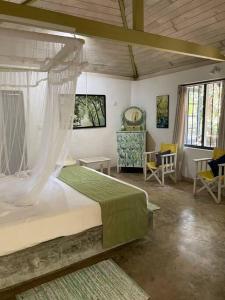 a bedroom with a bed with a canopy and chairs at Diklande Estate Bungalow in Negombo