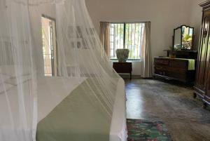 a bedroom with a bed with a mosquito net at Diklande Estate Bungalow in Negombo