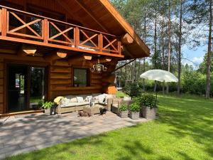 un porche de una cabaña de madera con sofá y sombrilla en Wikno Villa, en Nidzica