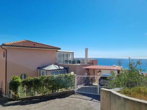 een huis met een hek en de oceaan op de achtergrond bij Dernier étage d'une maison in Roquebrune-Cap-Martin