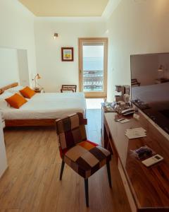 um quarto com uma cama e uma secretária com uma televisão em Domus Maris Relais Boutique Hotel em Sciacca