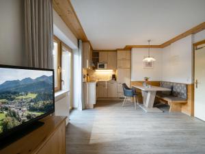 ein Wohnzimmer mit einem TV und einer Küche in der Unterkunft Gästehaus Gollner in Fieberbrunn