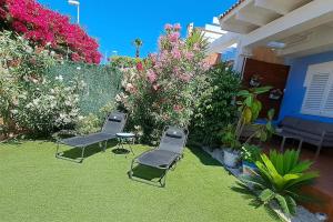 due sedie e un tavolo in un cortile fiorito di Awesome cozy bungalow , pool open from june to september a Gran Alacant