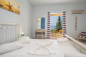 Schlafzimmer mit einem weißen Bett und Meerblick in der Unterkunft Agnanti Studios in Lourdata