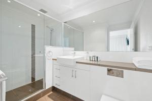 een witte badkamer met een wastafel en een spiegel bij Dolphin Quay Apartments in Mandurah