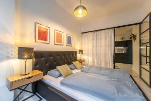 a bedroom with a large bed and a night stand with a lamp at Sunny Central Apartment on Wenceslas Square by easyBNB in Prague