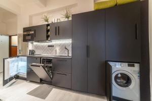 kuchnia z szarymi szafkami, pralką i suszarką w obiekcie Sunny Central Apartment on Wenceslas Square by easyBNB w Pradze