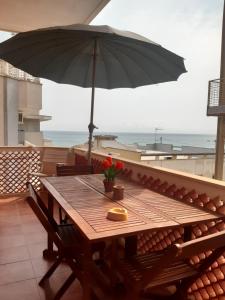 a wooden table with an umbrella on a balcony at TERRAZZA LA LOGGIA - Appartamento Panoramico in San Foca