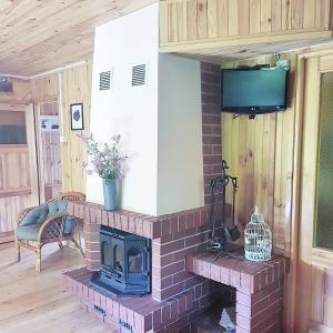a brick fireplace in a living room with a tv at Sarni Zakątek in Rybno