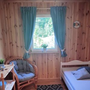 a bedroom with a bed and a window with a chair at Sarni Zakątek in Rybno