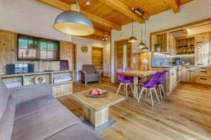 a kitchen and living room with a table and purple chairs at Ferienwohnungen Holzferienhäuser Leithenwald in Zwiesel