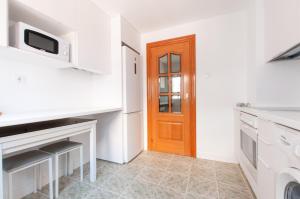 a kitchen with white counters and a wooden door at VALERIA-DREAMS Maestro Luna 3º in Zaragoza +8 photos