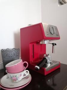 eine rote Kaffeemaschine und eine Tasse auf dem Tisch in der Unterkunft Charmante suite indépendante en maison de village in Loriol-sur-Drôme