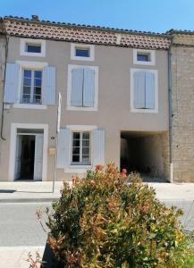 un edificio con ventanas blancas y un arbusto delante de él en Charmante suite indépendante en maison de village, en Loriol-sur-Drôme