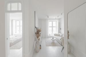un soggiorno bianco con divano e specchio di Downtown Apartments Old Town Pure White a Danzica