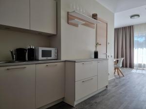 cocina con armarios blancos y microondas en Aisa Holiday Apartment, en Pärnu