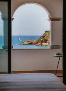 a bedroom with a window with a sailboat in the ocean at Casa Indiana Hotel Boutique in Blanes