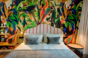 a bedroom with a large bed with a colorful mural at Casa Indiana Hotel Boutique in Blanes
