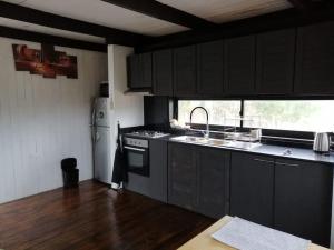 uma cozinha com armários pretos, um lavatório e um frigorífico em El Racó - Kitesurf Sirena - Cabaña frente al mar em Curanipe