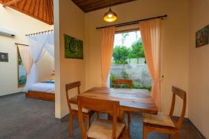 una sala da pranzo con tavolo e sedie in legno e una finestra di villa ambara sumberkima a Banyuwedang