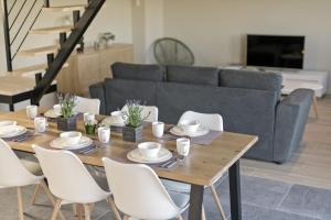 mesa de comedor con sillas blancas y sofá en Les Petits Sablens 