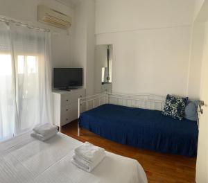 a white bedroom with two beds and a television at Alma Sea House in Hanioti