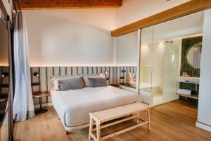 a bedroom with a white bed and a bench at Casa Indiana Hotel Boutique in Blanes