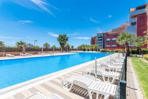 a swimming pool with white lounge chairs next to a building at Las Palmeras by Ĥ - Playa Punta del Moral PLHP28P11 in Isla del Moral